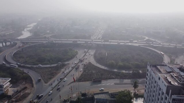 Aerial view of traffic across cloverleaf interchange of Maduravoyal flyover Bridge under hazy polluted sky, Chennai, India