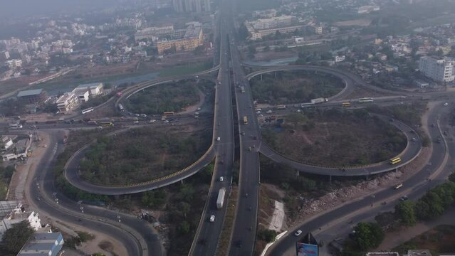 Cinematic aerial view of the iconic cloverleaf interchange of Maduravoyal flyover Bridge with smooth flowing traffic, India
