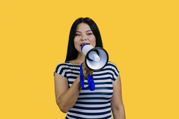 Fototapeta premium Young asian woman saying something in a megaphone. Isolated on yellow.