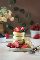 Mini pancakes with fresh berries on a ceramic plate, perfect for a sweet brunch.