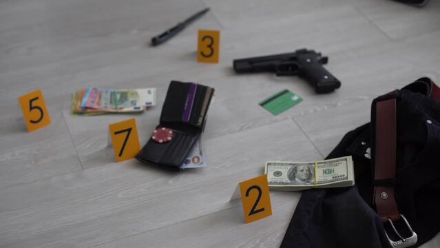 Crime scene investigation - numbering of evidences after the murdering in apartment. Brass knuckle, wallet and clothes with evidence markers