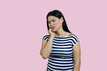 Young asian woman is suffering from toothache. Isolated on pink background.