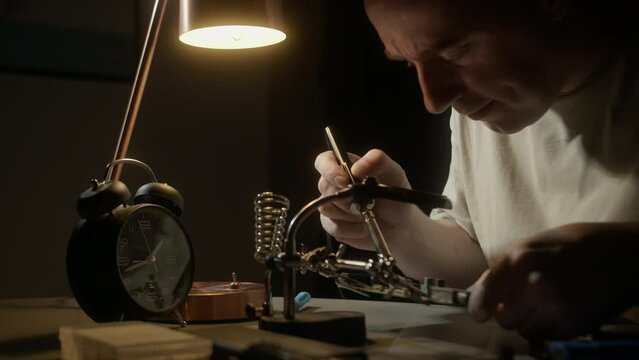 Repairing a microcircuit, smoke from soldering iron.Disconnect radio components.Scheme with precious metal, gold.Man solders Transistors, RadioElectronic Parts on Electronic Board with Soldering Iron.