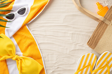 Tropical vibes concept. Top view of summer essentials: sunglasses, beach bag, flip-flops, bikini, sunscreen, towel, palm leaves. Empty space for text or advertisement on sandy beach backdrop © ActionGP