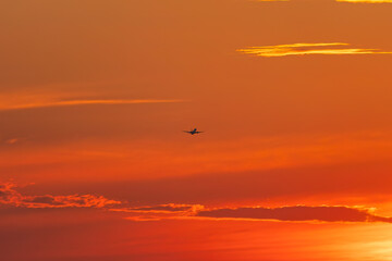 An airplane in the sky after takeoff at sunset.