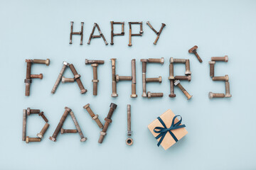 Happy fathers day greeting lettering text from vintage screws and gift box top view on blue...