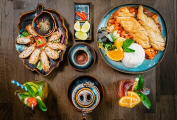 Top view of a table with gourmet Asian dishes like bun cha, fried chicken and iced lemonade