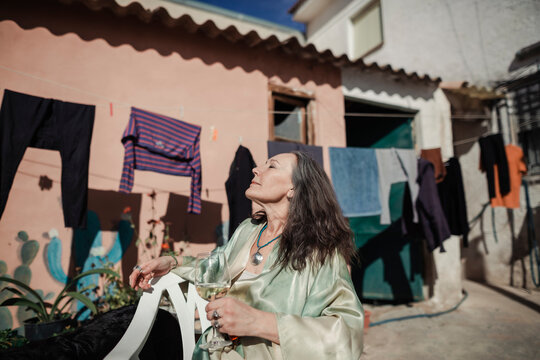 Woman drinking wine next to hanging clothes in a yard