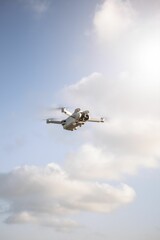 Vertical shot of a quadcopter flying in the sky in a sunny day