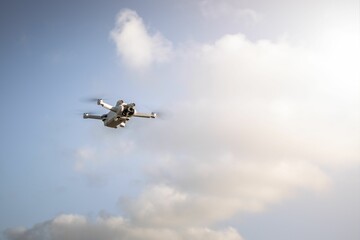 White quadcopter flying in the sky on a sunny day