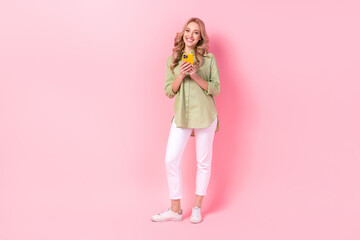 Full length photo of sweet adorable lady wear green shirt chatting modern gadget empty space isolated pink color background