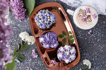 Floral lilac cupcakes, aesthetics desserts, coffee cup with melted marshmallow among lilac flowers...