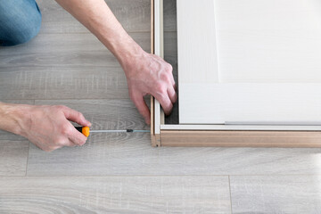 Worker tightens a door frame with a screw. Repair and decoration of apartments. Installation and...