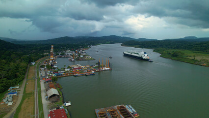 Dark rain clouds rolling over port and cargo ship passing through Panama Canal