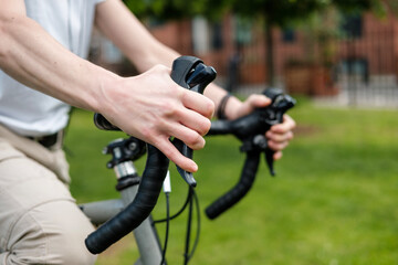Close-up of hands on handlebar bike in park.