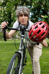 Naklejka premium Androgynous non-binary person with a bike in a park.