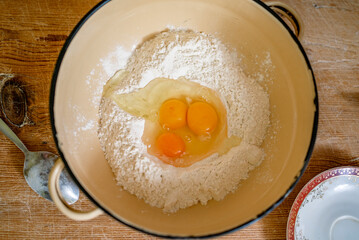 grandmother kneads dough, prepares noodles in the kitchen at home. Senior woman hands are rolling out dough in flour with a rolling pin in her home kitchen. 