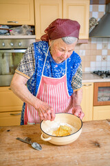 grandmother kneads dough, prepares noodles in the kitchen at home. Senior woman hands are rolling out dough in flour with a rolling pin in her home kitchen. 