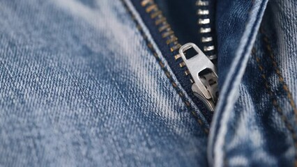 unbuttoned zipper on blue jeans. the rotation of the fabric of blue jeans in closeup details. the concept of tailoring. denim texture, abstract background.