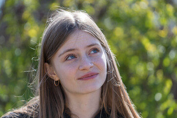 Portrait of a dreaming beautiful young girl on the background of nature, closeup, outdoors