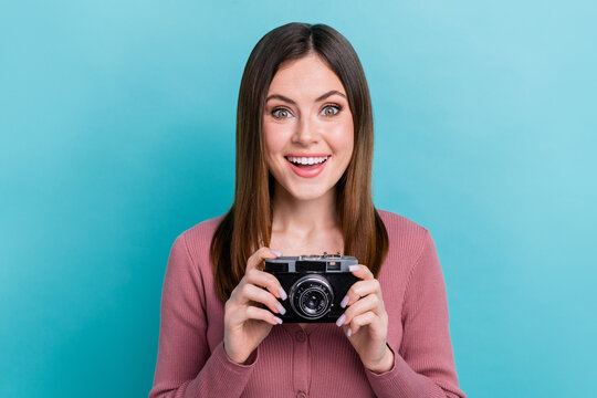 Portrait of cheerful funny girl wear pink shirt hold vintage photo camera free time hobby paparazzi isolated on cyan color background
