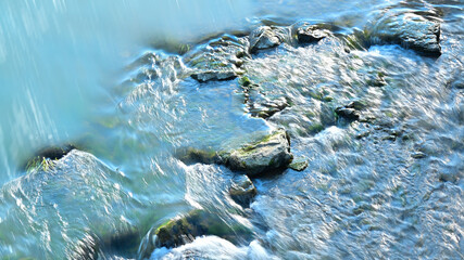 Close up of running water in a stream creek with rocks.