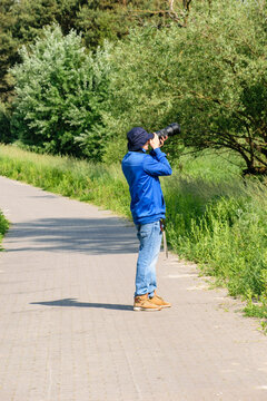 Mężczyzna fotografujący ptaki na drzewie aparatem z teleobiektywem