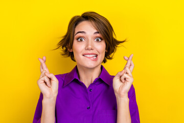 Photo of young nervous woman bite lips crossed fingers wear violet shirt anticipation expectations...