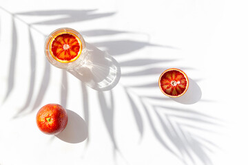 Creative composition made of half bloody red orange and a glass with cocktail on white background...