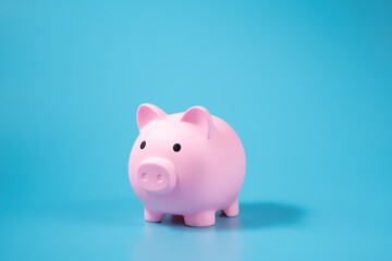 A pink piggy bank on blue background with copy space.