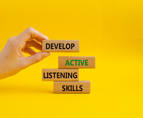 Listening skills symbol. Concept word Develop active listening skills on wooden blocks. Beautiful yellow background. Businessman hand. Business and Develop active listening skills concept. Copy space