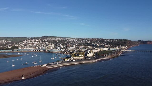 Teignmouth, South Devon, England: DRONE AERIAL VIEW: The drone flies towards Teignmouth commercial dock (blue buildings, left of picture), the town of Teignmouth, River Teign estuary &Teignmouth Pier.
