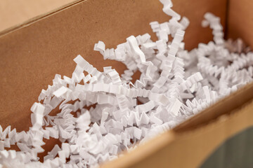 Open cardboard box with white shredded plastic filler
