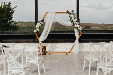 Wedding wooden arch in rustic style decorated with white flowers and greenery. Wooden hexagonal...
