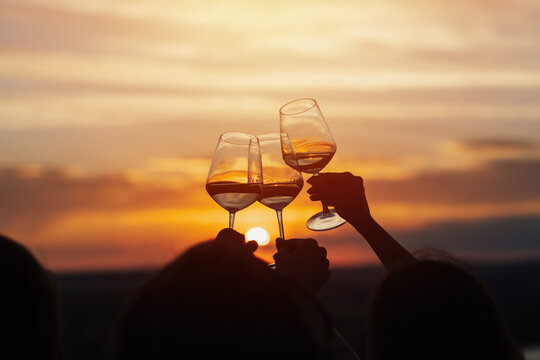 A group of girlfriends raise a toast with glasses of white wine on a sunset. Close shot.	

