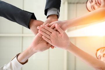 Happy united business team joins hands as a sign of business teamwork. stacking hands celebrating...