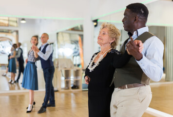 Man and mature woman learning to dance classical ballroom dance
