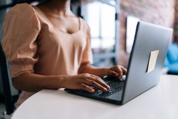 Close-up hands of unrecognizable African female student typing on notebook keyboard studying working online. Closeup of black businesswoman typing on laptop computer at desk from remote home office.