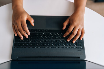 Fototapeta na wymiar Closeup high angle view hands of unrecognizable African American businesswoman press on keyboard keys, typing on laptop keyboard working online. Black female freelancer working from remote home office