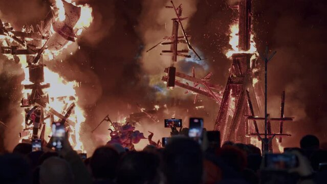People capture the burning ninot dolls on their mobile phones at night. Celebration of Fallas on the streets of Valencia, Spain