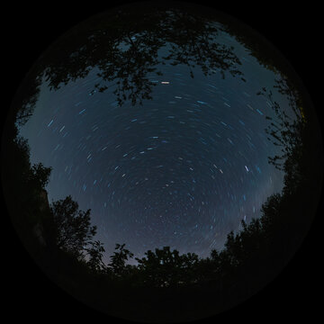 Star trails in the form of lines in the night sky with a long exposure. The movement of stars around the North Celestial Pole of the polar star. Fulldome format