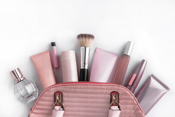 Glamorous pink women's handbag with cosmetics laid out on a white background. Space for text.