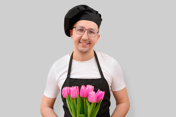 Happy chef holding flowers looking at camera on white background. The concept of cooking and people