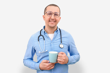 Male doctor with a cup of coffee or tea looks at the camera on a white background.
