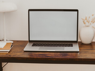 Laptop with blank screen on wooden table in home interior.
