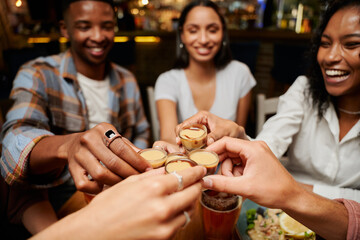 Young multiracial group of friends in casual clothing doing celebratory toast with drinks at restaurant