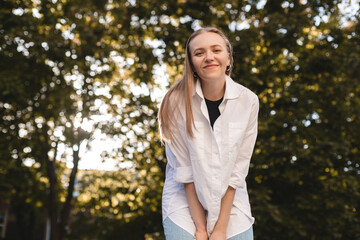 Overjoyed happy woman enjoying the green beautiful nature woods park around her. Concept of female people and healthy natural lifestyle - happiness emotion and woman look at camera.