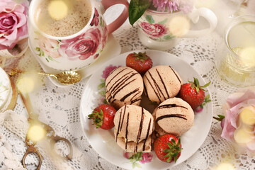 Mini meringue cookies with strawberries and cappuccino on the table in vintage style top view