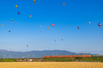 特急列車と快晴の空を飛行する熱気球