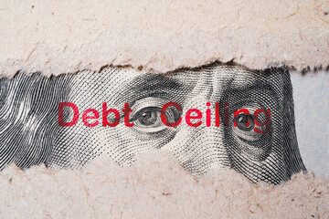 Benjamin Franklin face from USD dollar banknote behind of torn paper with debt wording for...